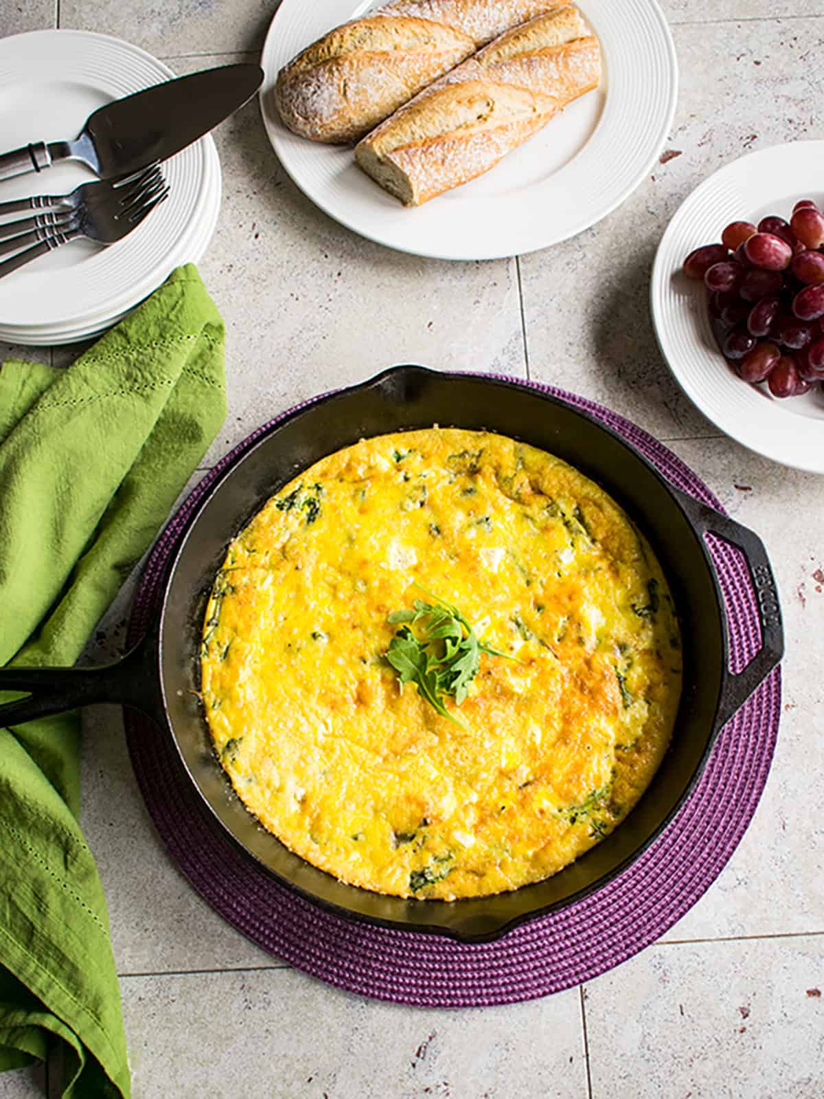 arugula frittata in cast iron pan garnished with arugula