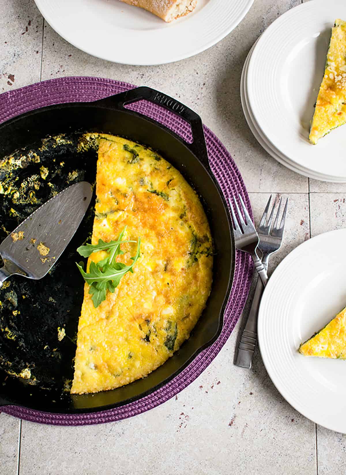 arugula frittata cut in half in a skillet