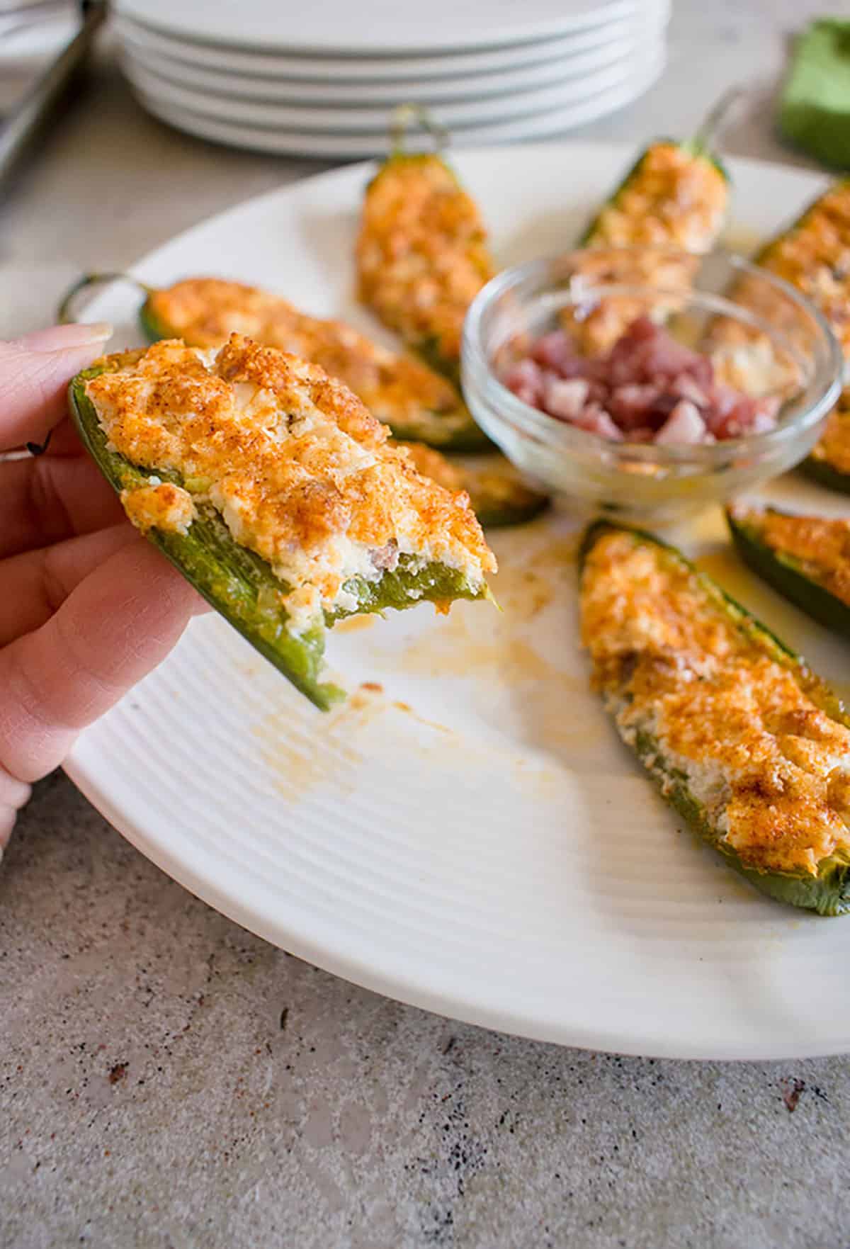 bitten jalapeño popper held over a platter