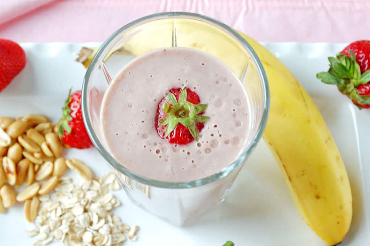 overhead shot of peanut butter and jelly smoothie in a glass with strawberries