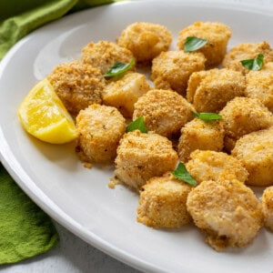 platter of breaded sea scallops garnished with basil leaves and lemon