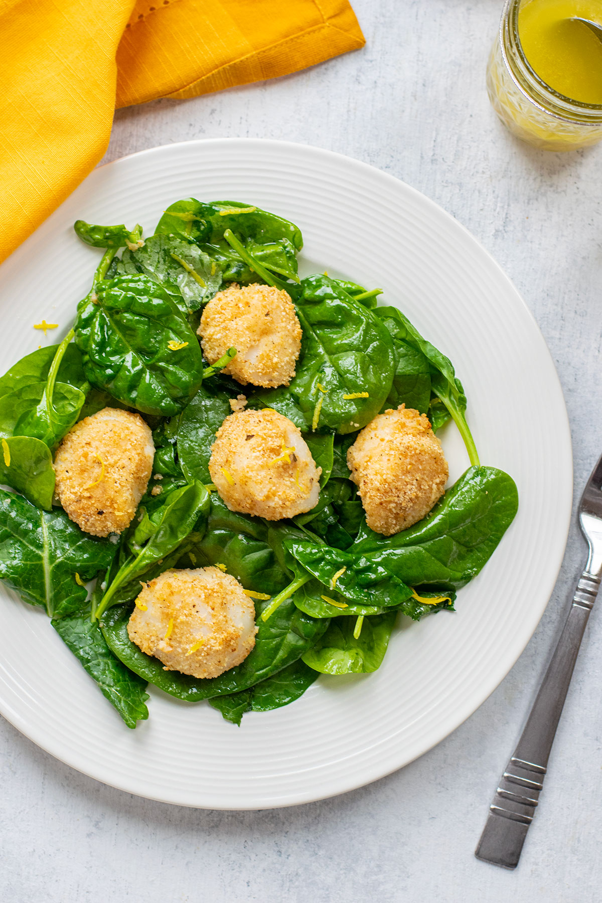 plate of spinach lettuce with breaded scallops