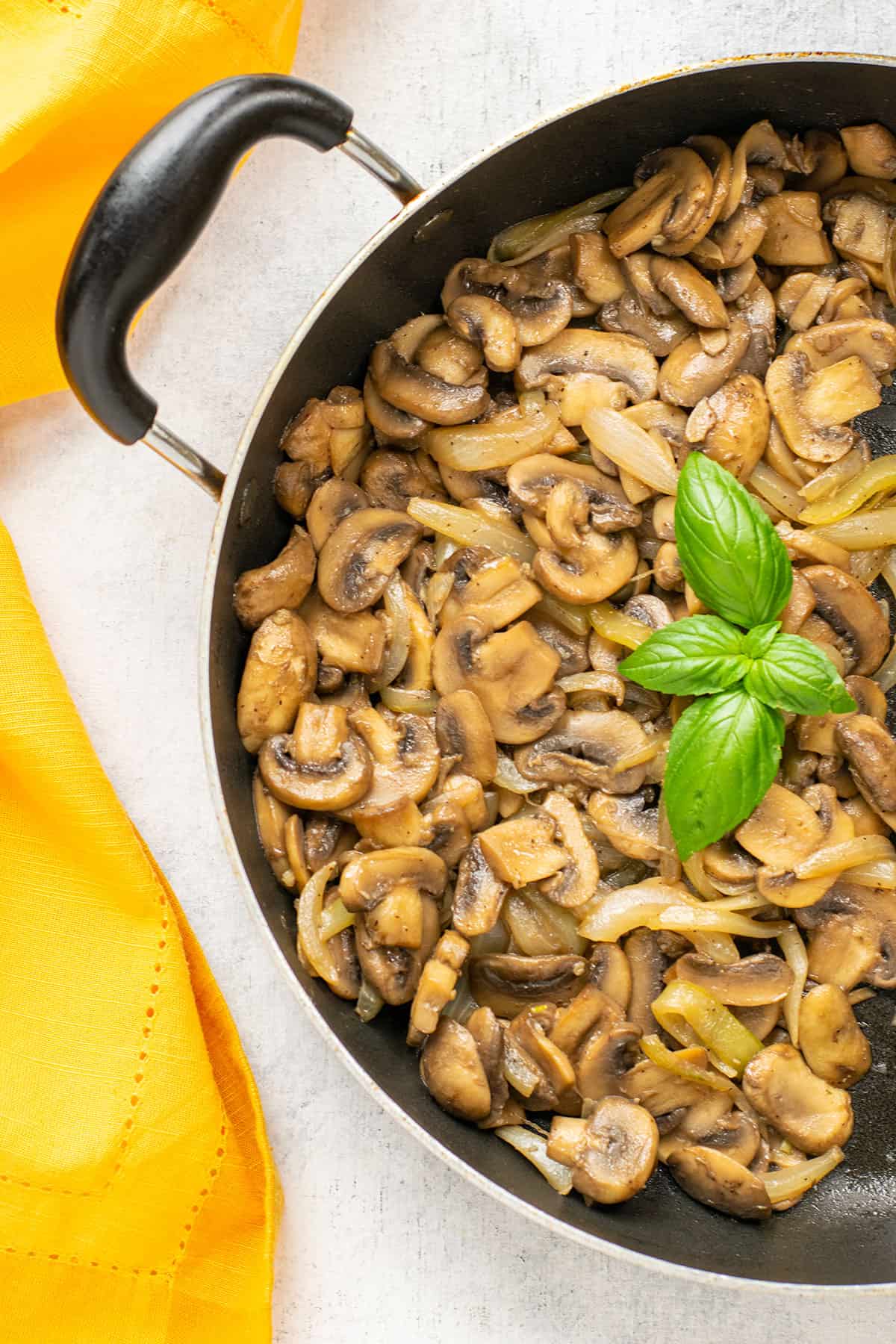 pan of sautéed mushrooms and onions garnished with basil