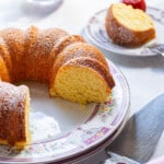 bundt cake cut on a dish with a slice and strawberries behind