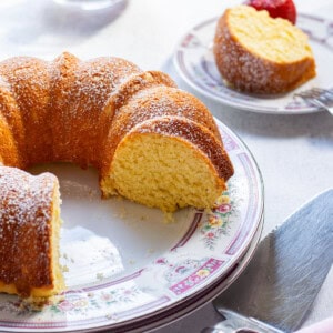 bundt cake cut on a dish with a slice and strawberries behind