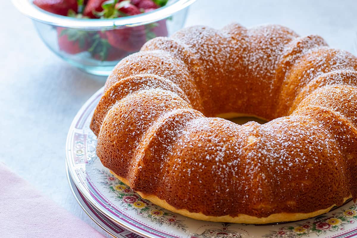 italian bundt cake on a dish with strawberries in the back