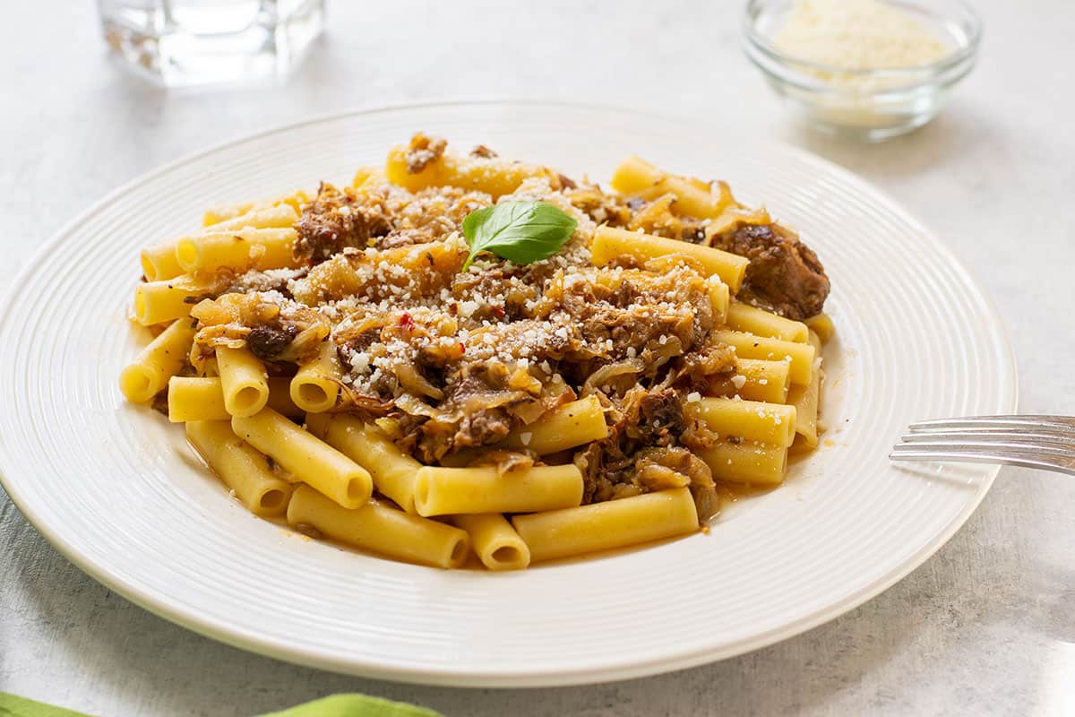 plate of ziti topped with Genovese sauce and basil