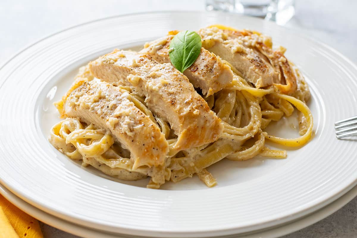 plate of chicken alfredo with fettuccine and basil
