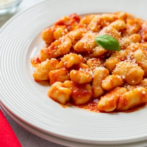 plate of homemade gnocchi topped with tomato sauce and basil