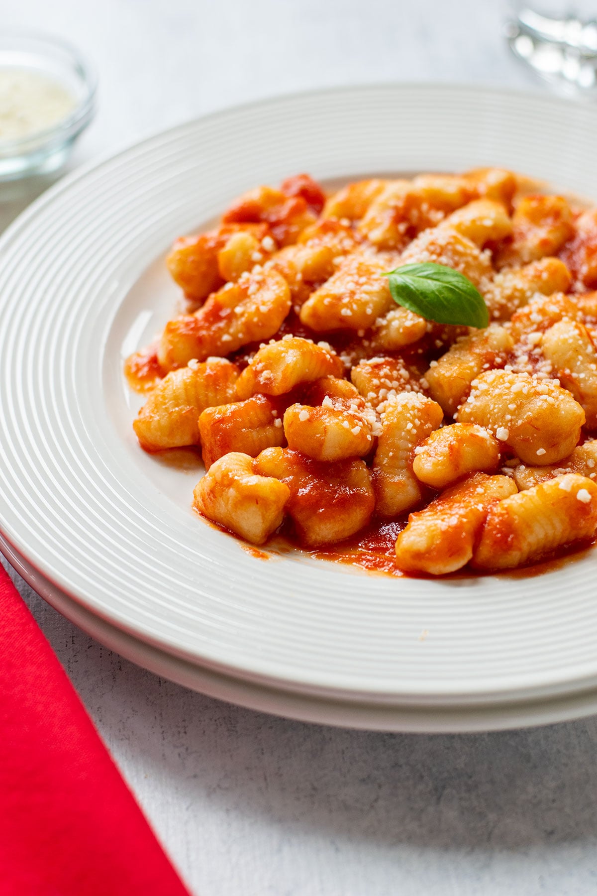 plate of homemade gnocchi topped with tomato sauce and basil
